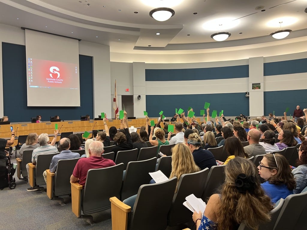 An images shows audience members at Tuesday night's Seminole County School Board meeting holding up placards to show whether they agreed or disagreed with the speaker. One side was red (showing disagreement) and the other side was green (showing agreement).